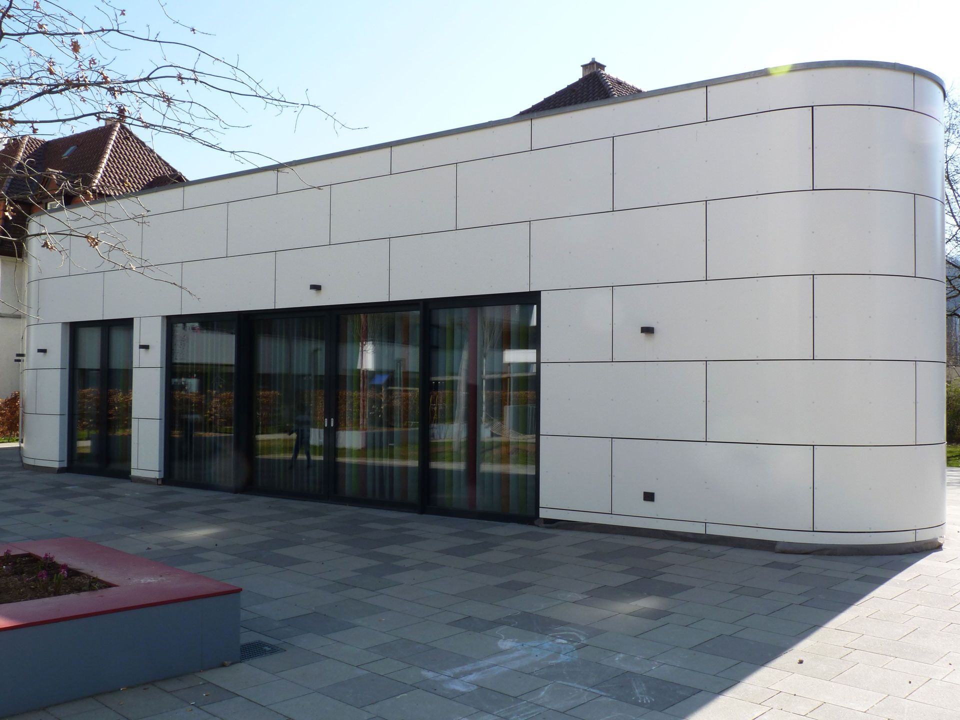 Das Bild zeigt ein Gebäude mit heller Fassade und einer Fensterfront.