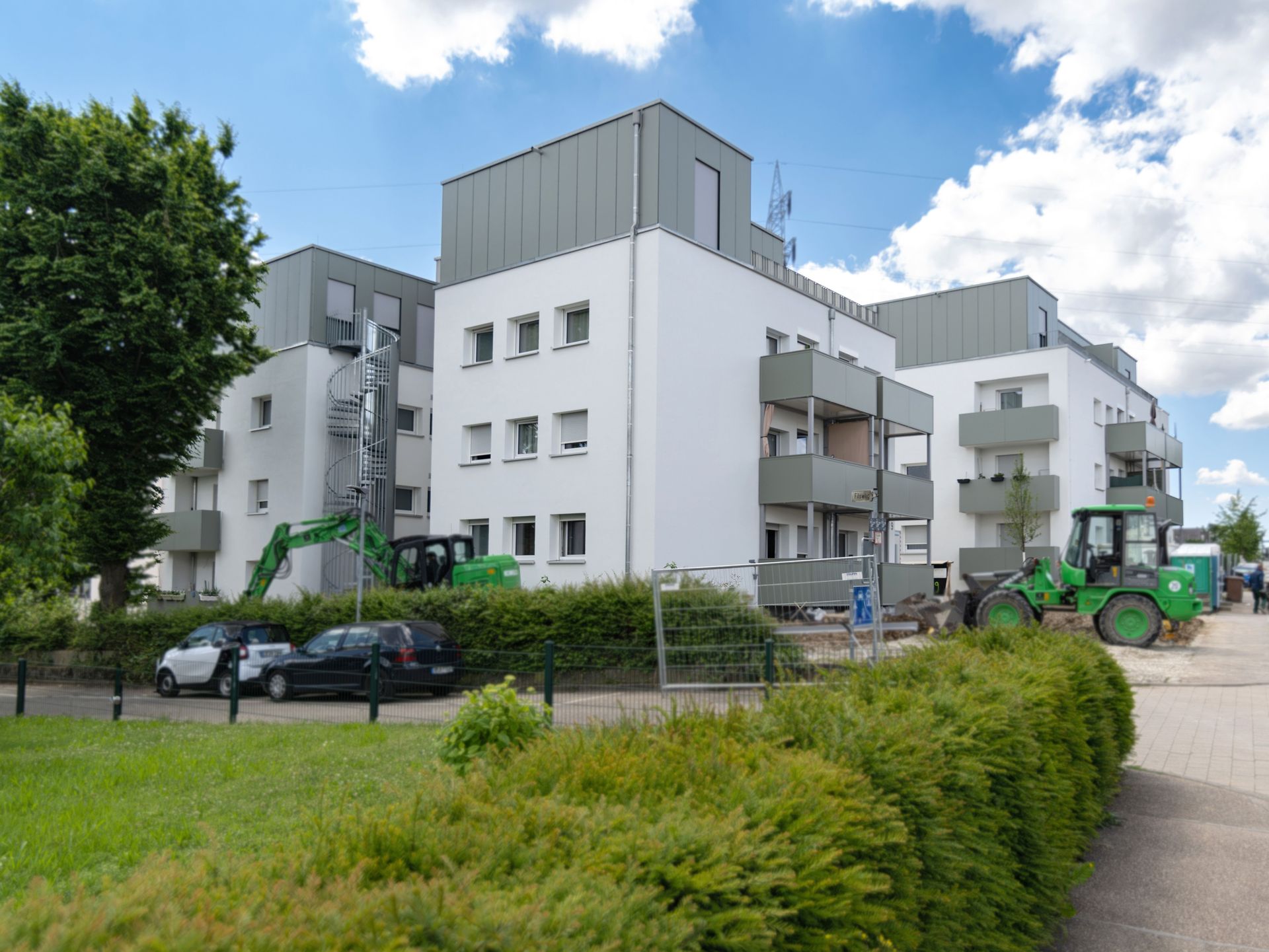 Das Bild zeigt mehrere Mehrfamilienhäuser, vor denen eine Baustelle ist. Man sieht Bagger und Baustellenzäune.