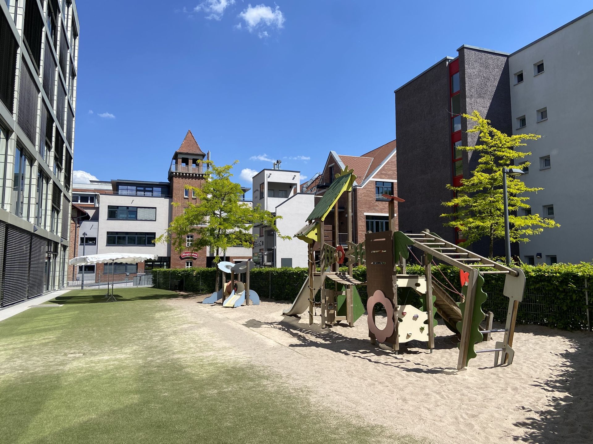 Das Bild zeigt einen Spielplatz zwischen mehreren Gebäuden.