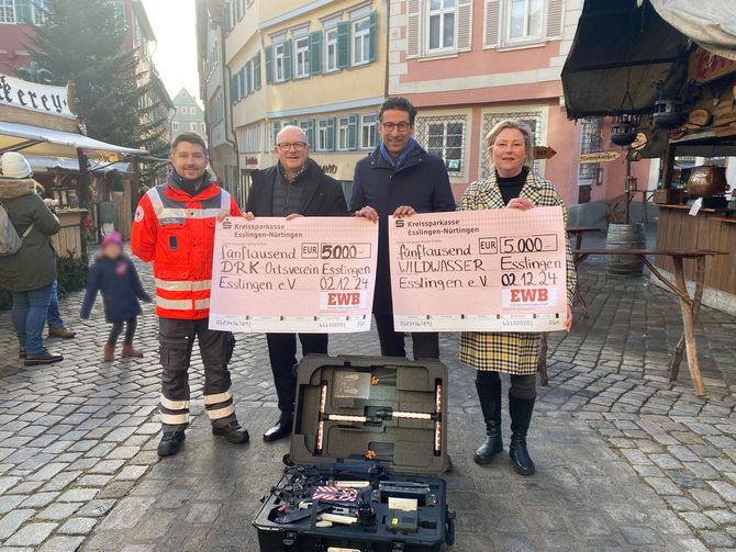 Das Bild zeigt 4 Personen die zwei Spendenchecks halten auf einem Marktplatz.