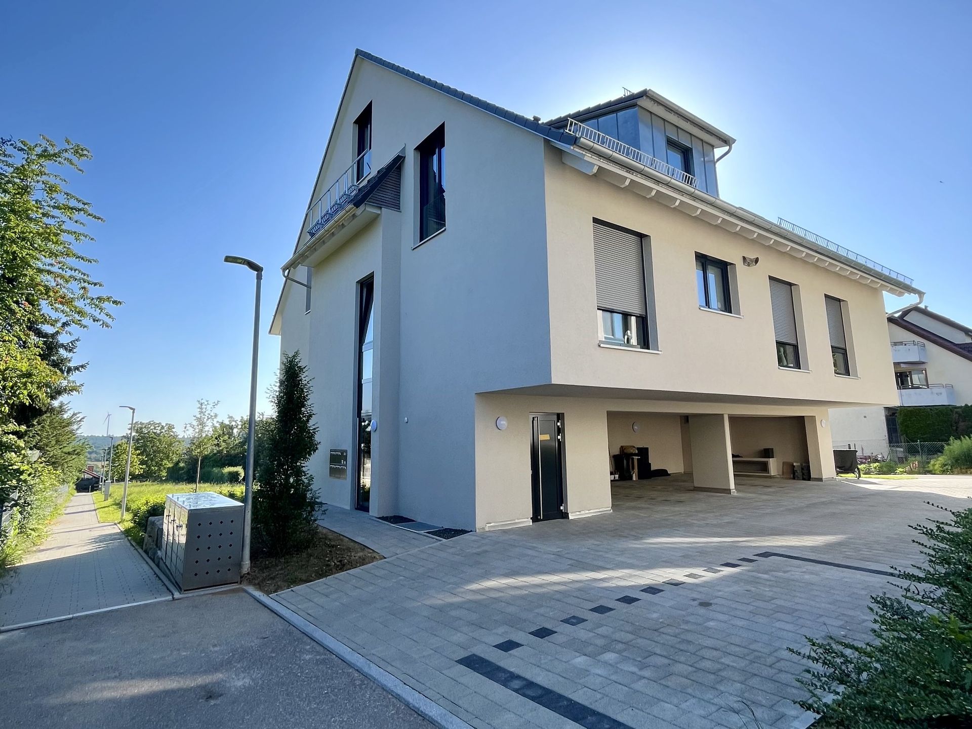 Das Bild zeigt ein Mehrfamilienhaus mit heller Fassade und einer Grünfläche um das Haus herum.