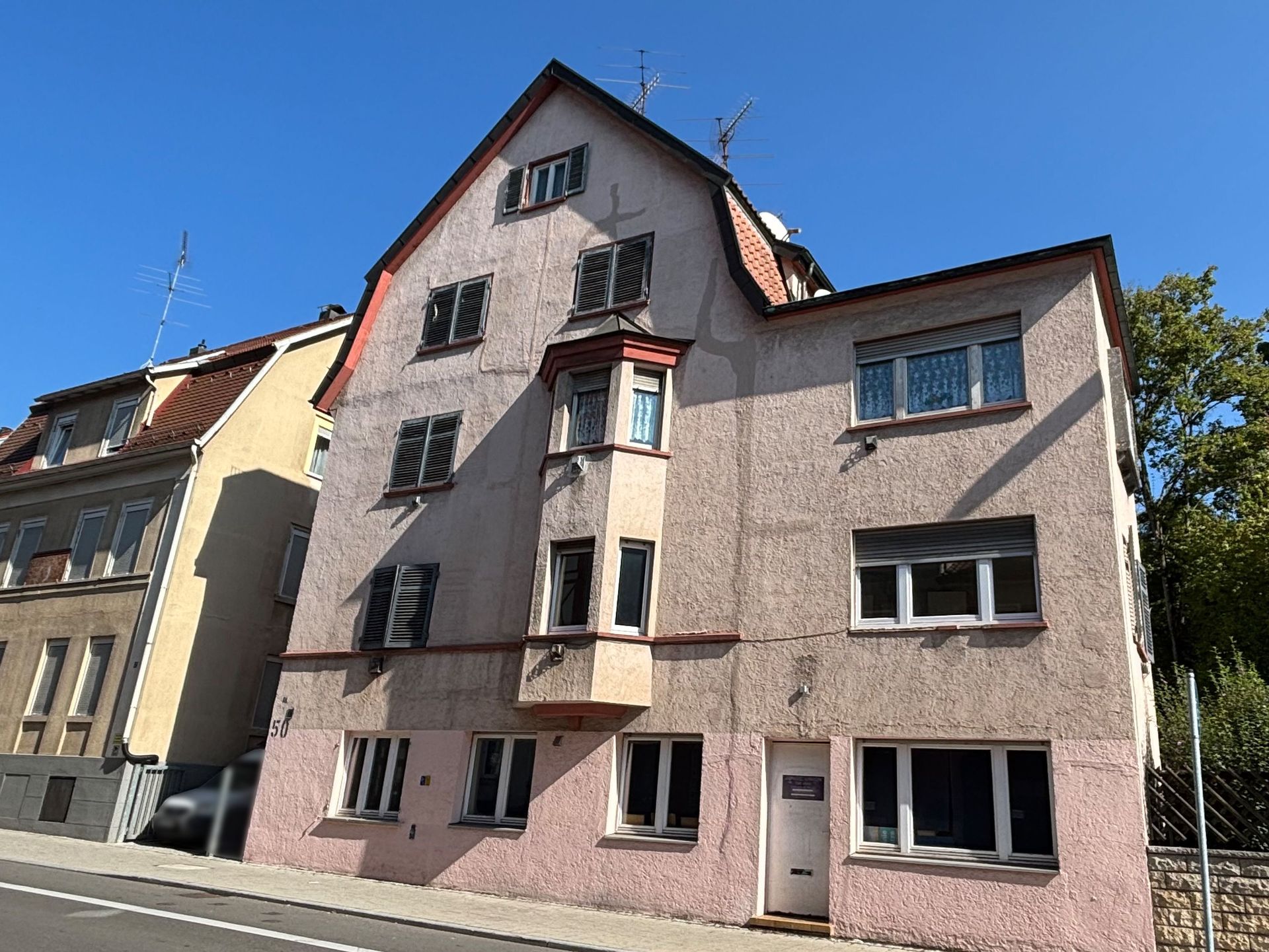 Das Bild zeigt ein Mehrfamilienhaus mit heller Fassade und einem Erker.