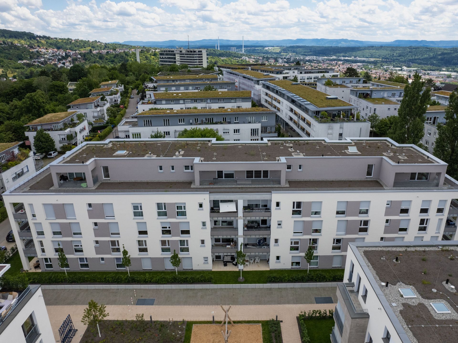 Das Bild zeigt mehrere Mehrfamilienhäuser. Die Fassaden sind weiß mit grauen Elementen.